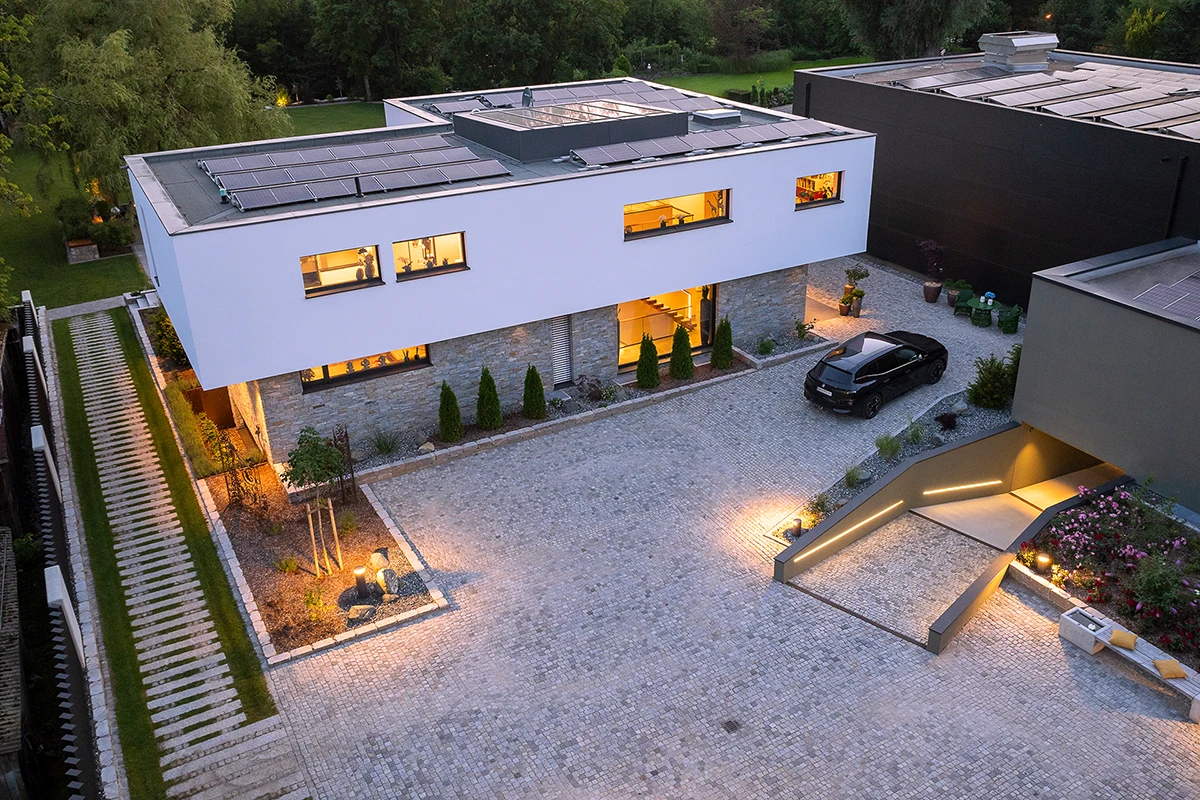 Modernes Einfamilienhaus mit eigener Tiefgarage aus der Vogelperspektive mit abendlicher Beleuchtung.